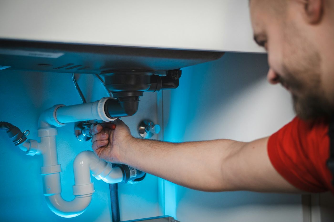 Plumber tightening a drain fitting under a sink
